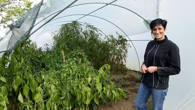 Mira in front of the vegetables she grows on her land